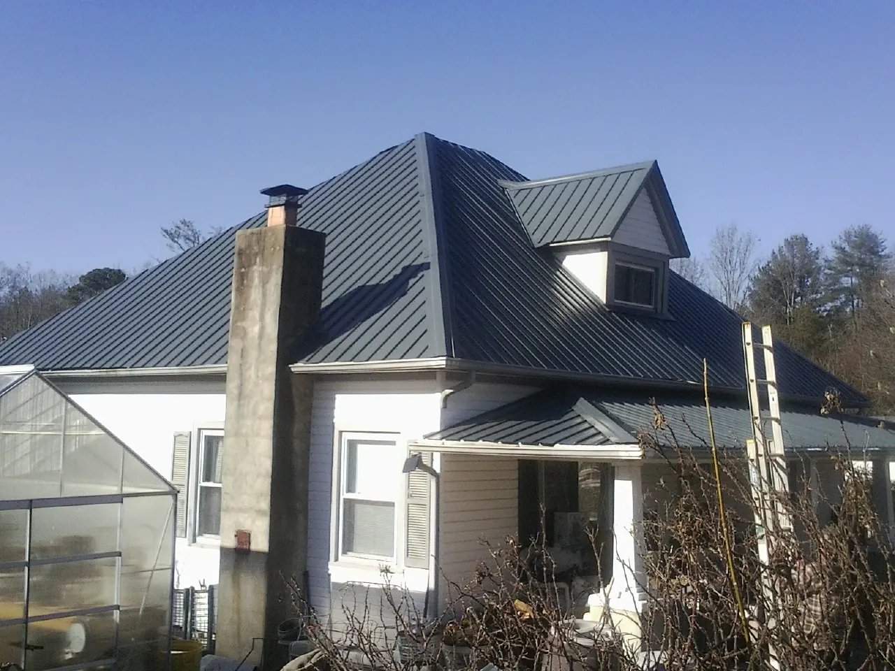 Dark blue standing seam metal roof on a white farmhouse with dormer — Slate & Tile Roof Repair by Roofing Brothers in Sylvania