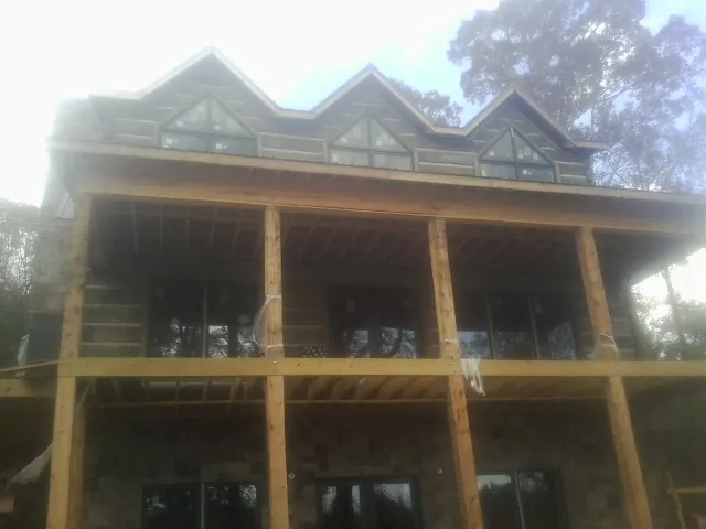 Dormers and porch framing on a large log home under construction — Roof Coating work by our crew in Sylvania